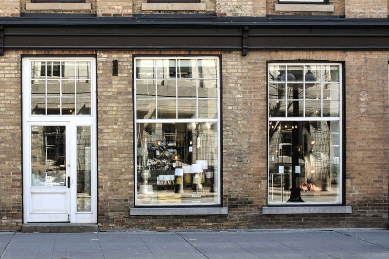 Brick shopfront with a white paneled door and two large, clean multi-pane display windows