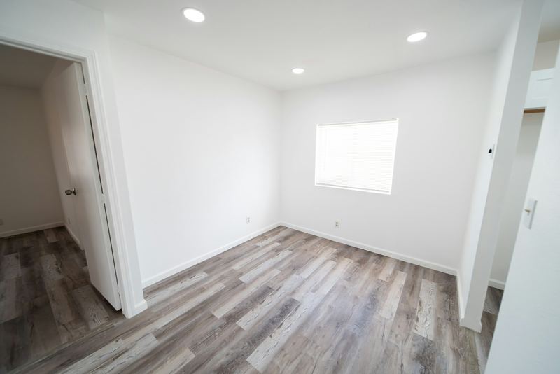 Freshly painted bedroom with smooth white walls, clean white trim and wood-look floors