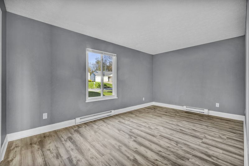 Empty room with freshly painted gray walls and crisp white baseboards
