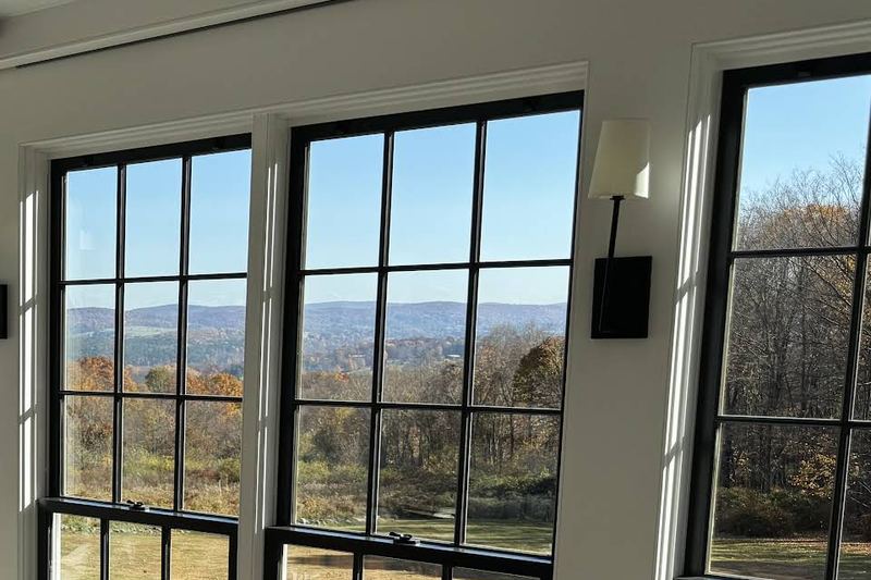 Sunroom with tall black-framed windows looking out over fall foliage and rolling hills